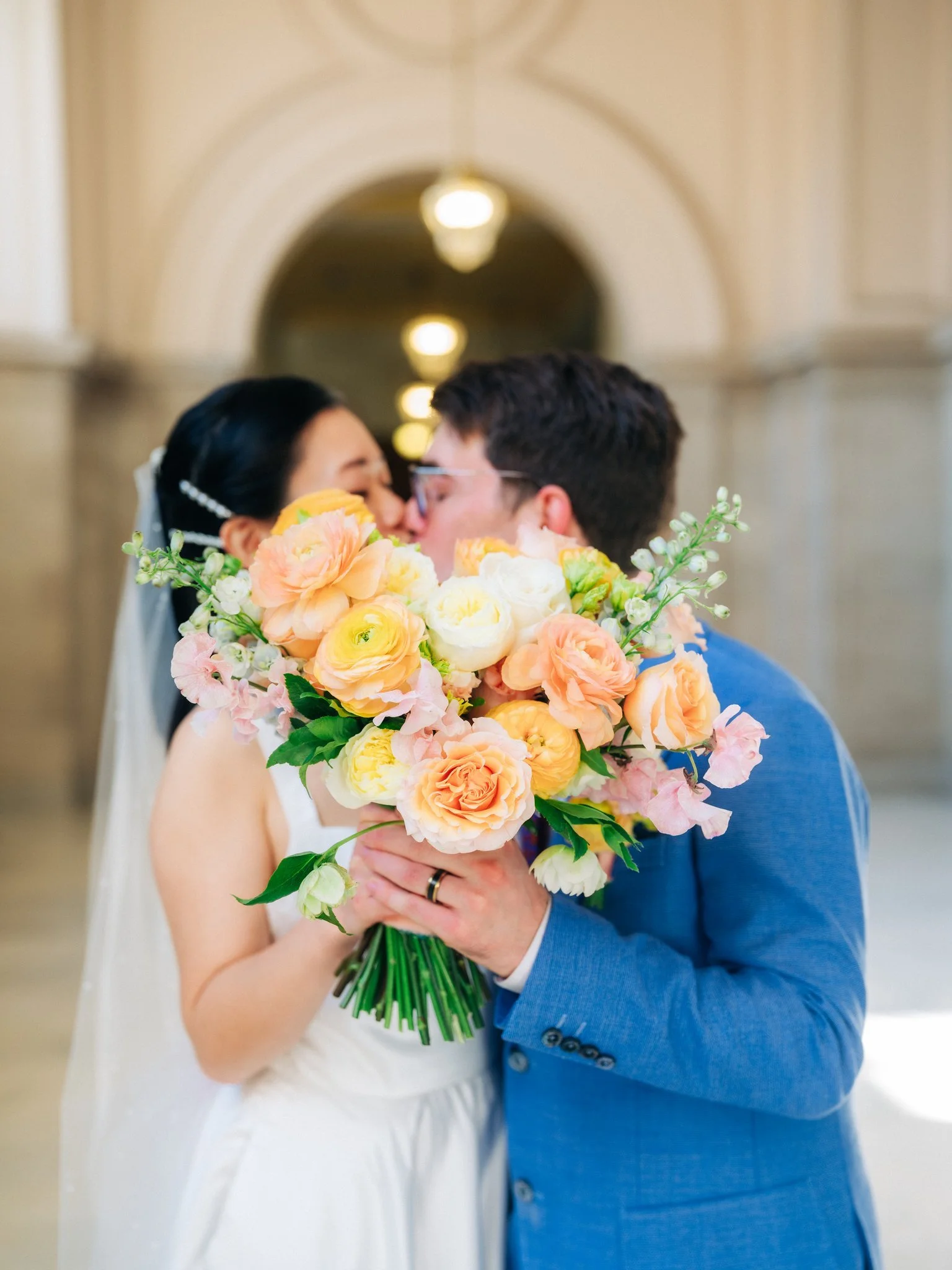 Bride and groom kissing with bouquet in foreground at San Francisco City Hall wedding