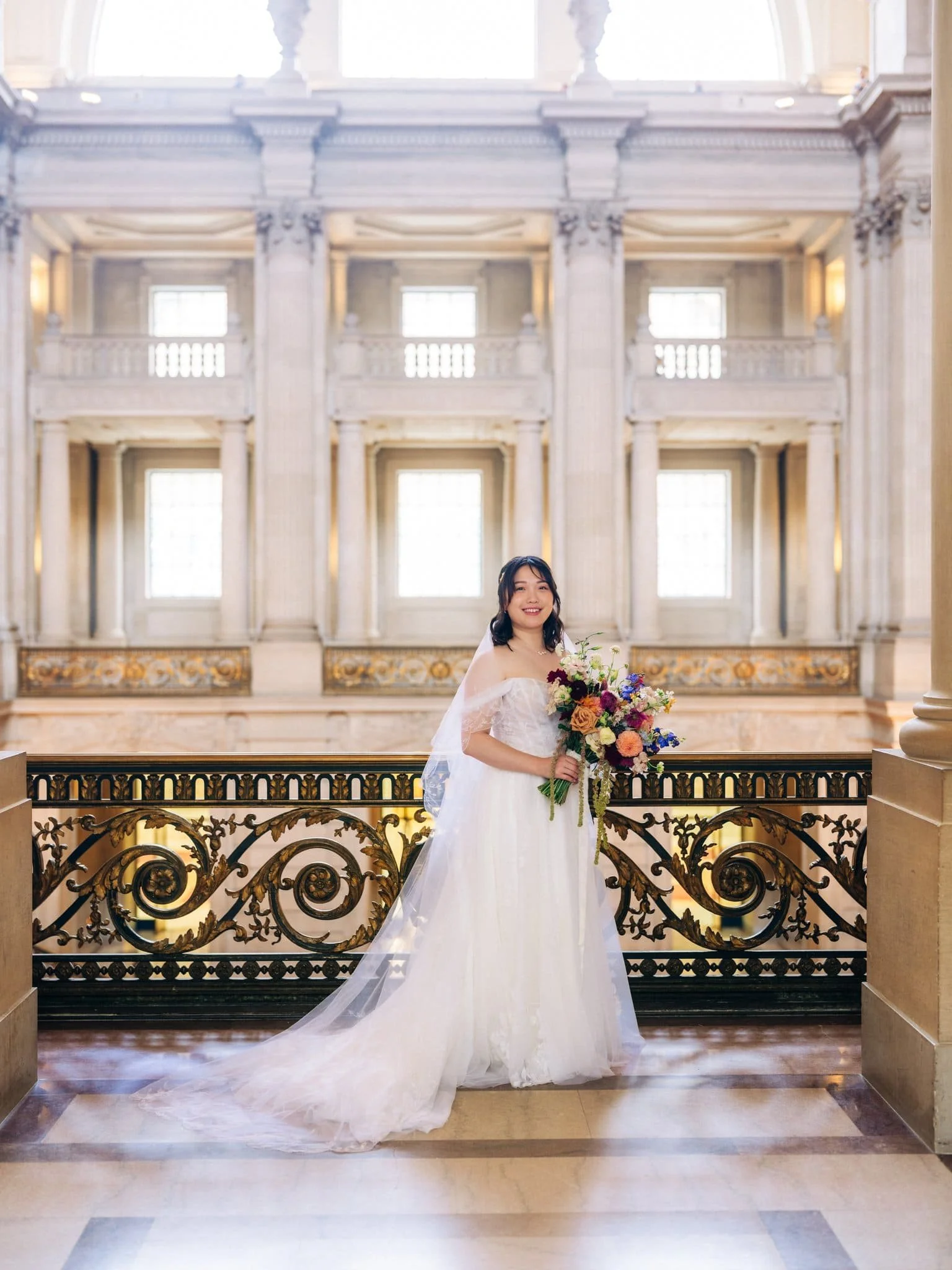Bride posing with her bouquet on a balcony during her San Francisco City Hall elopement.