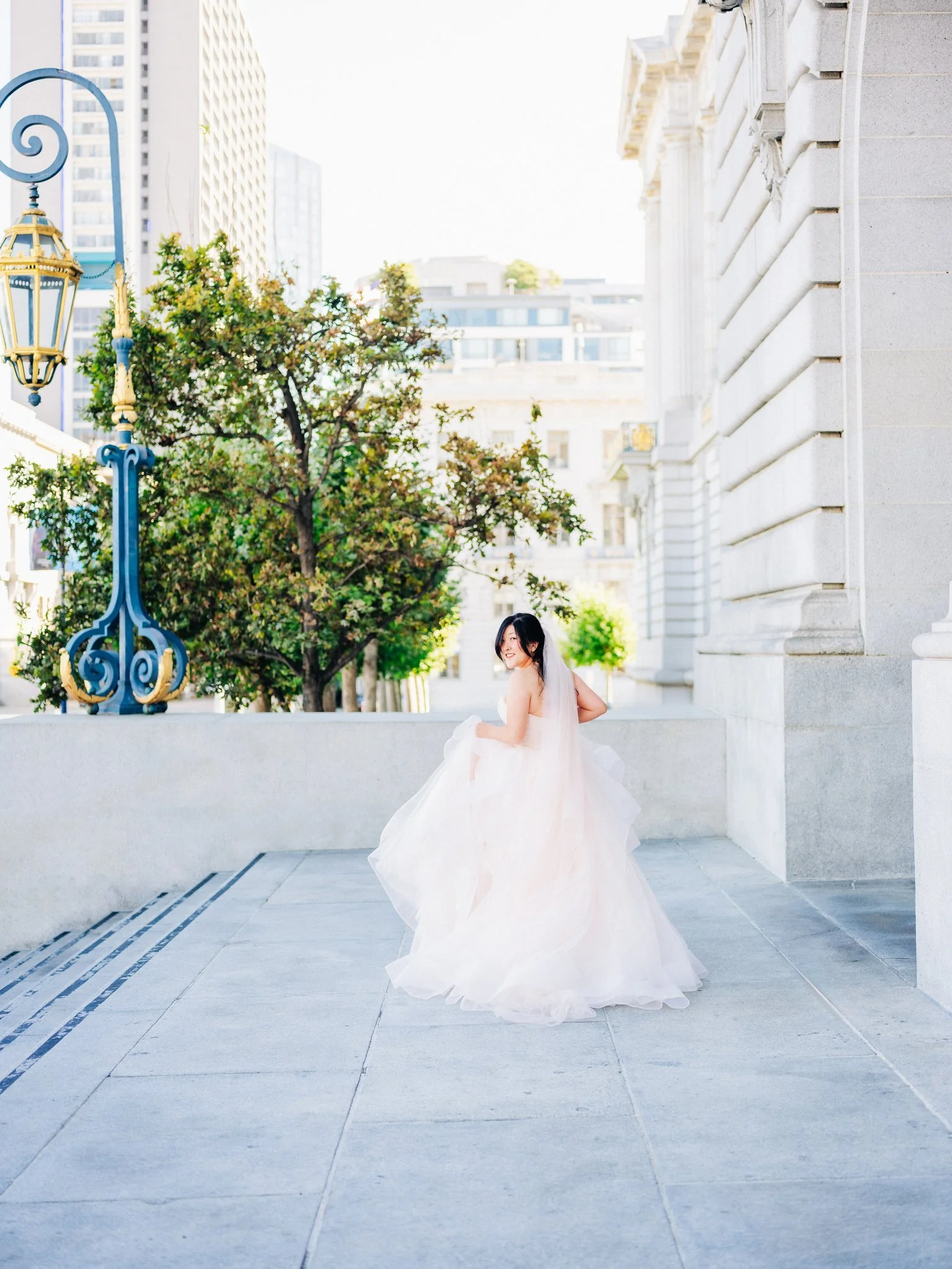 Bride posing on the steps of San Francisco City Hall before wedding ceremony