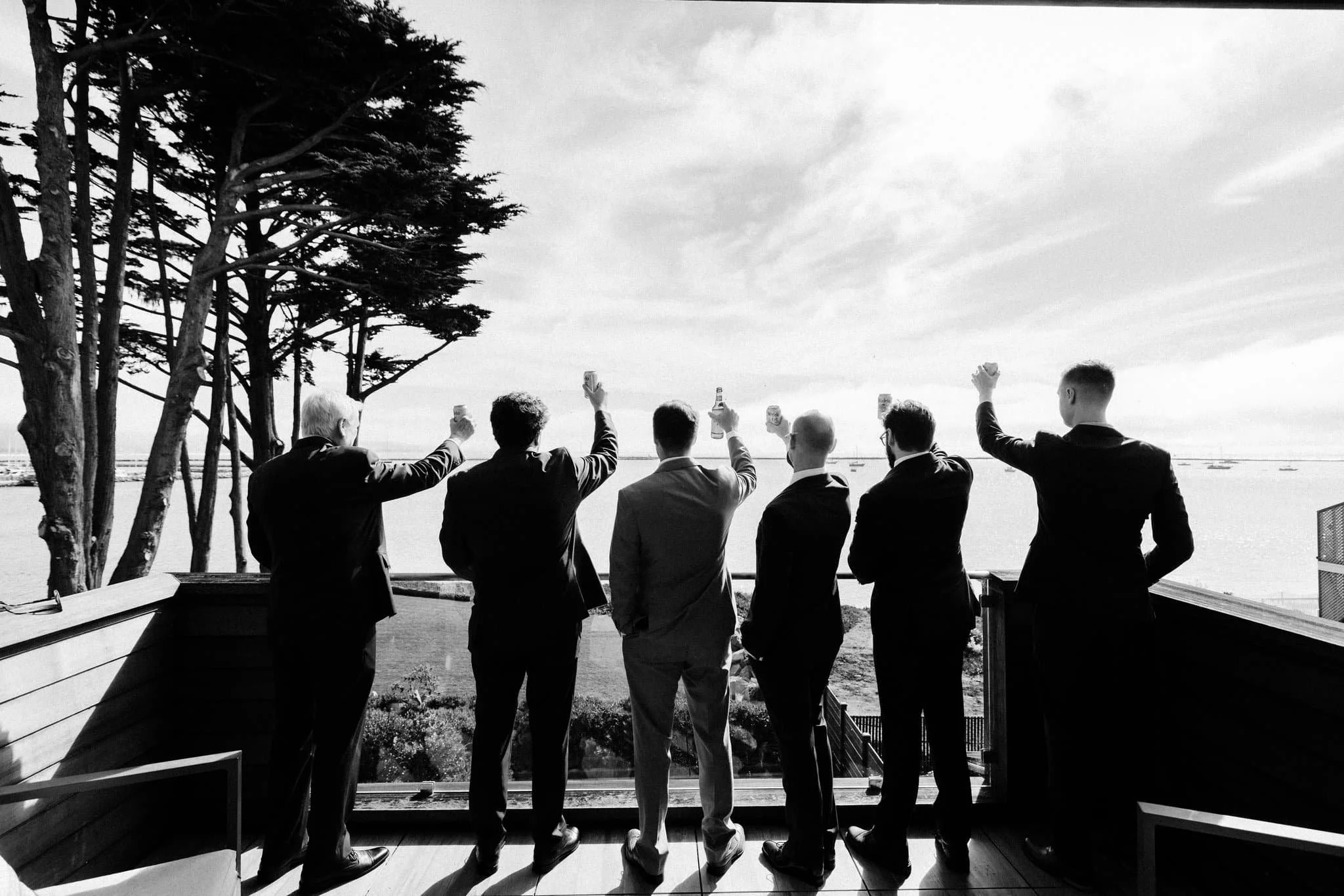 Groomsmen cheering drinks on oceanview deck at Maverick’s Beach House wedding in Half Moon Bay