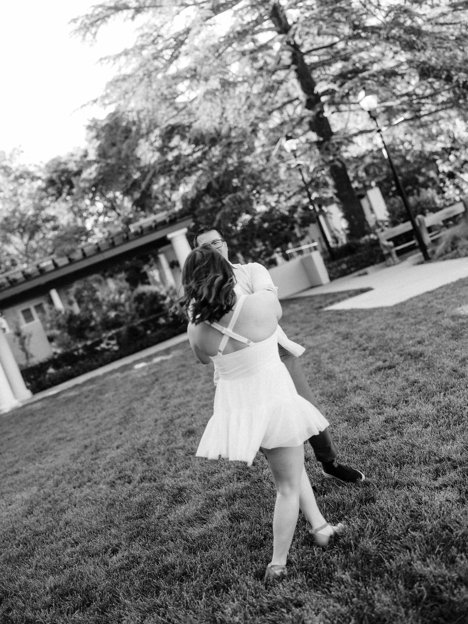 Couple holding hands and swinging in a circle on the grass during their Montalvo Arts Center engagement photos in Saratoga.