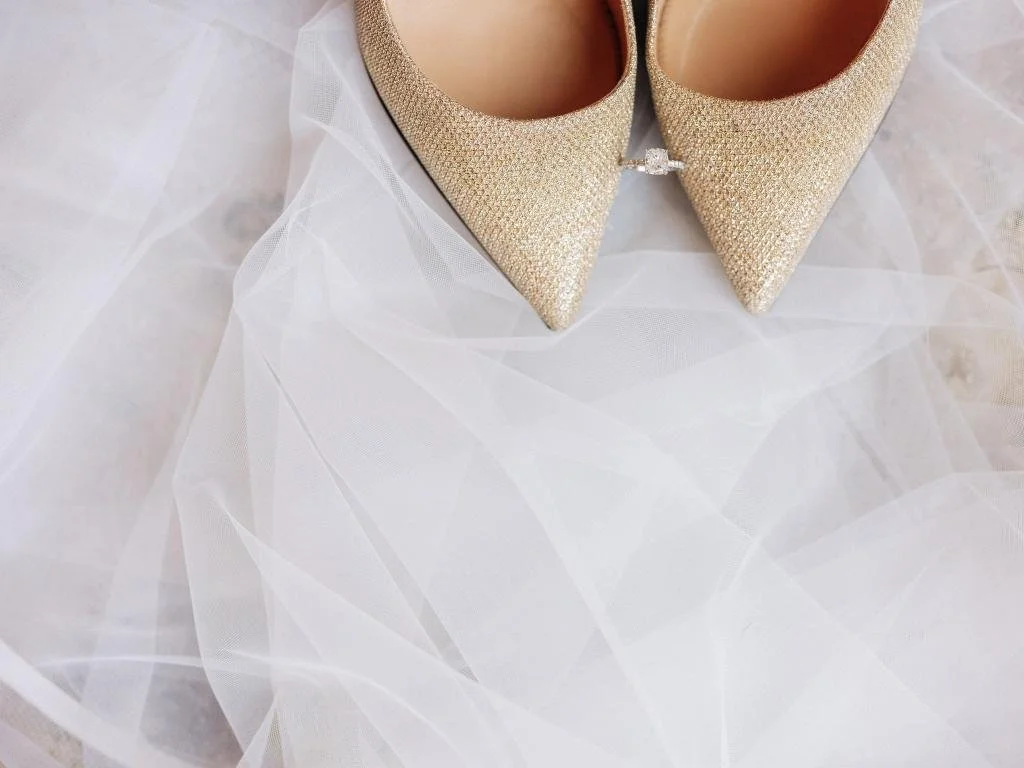 Bride's ring photographed between her wedding shoes