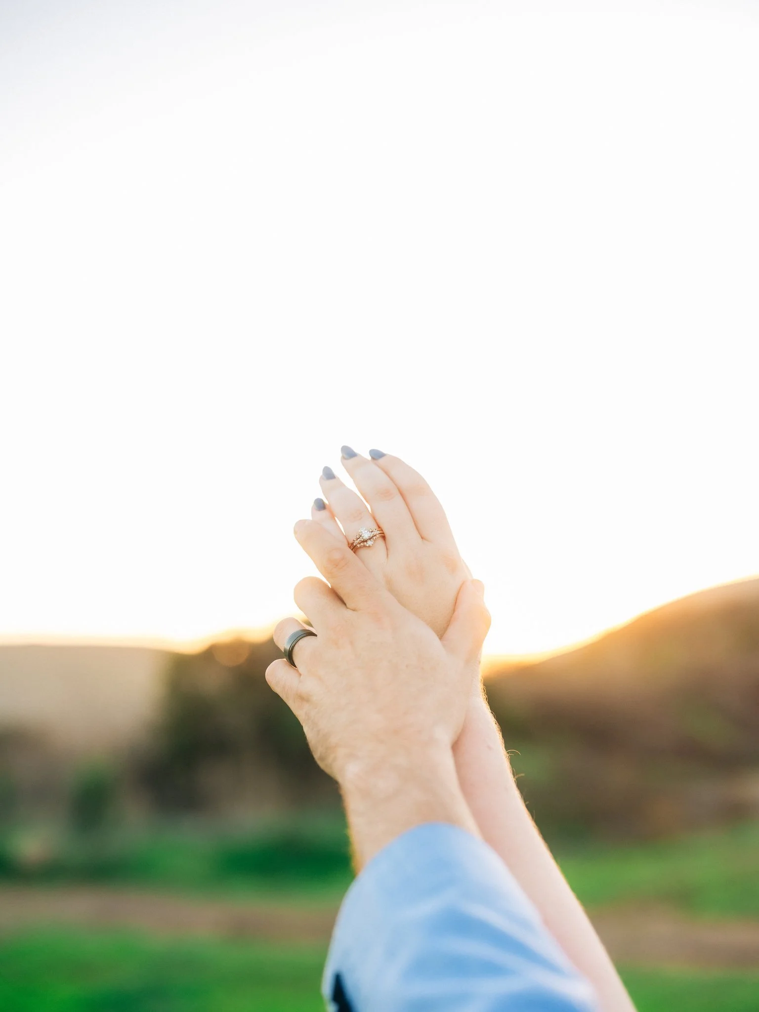 Close-up of wedding rings with mountains in the background at Coyote Hills Regional Park in Fremont CA