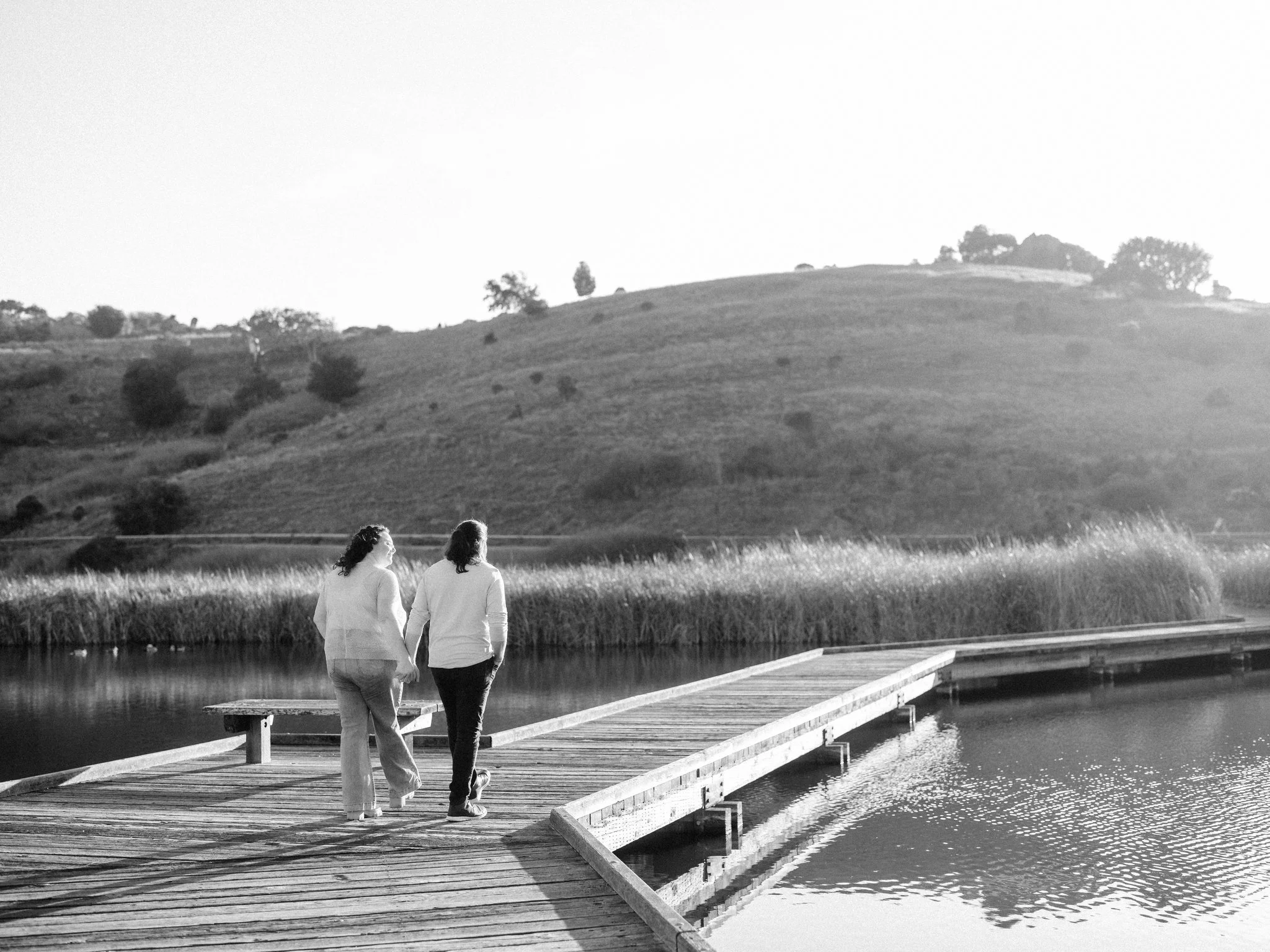 Couple holding hands walking down a dock during a couples photo session at Coyote Hills Regional Park in Fremont CA
