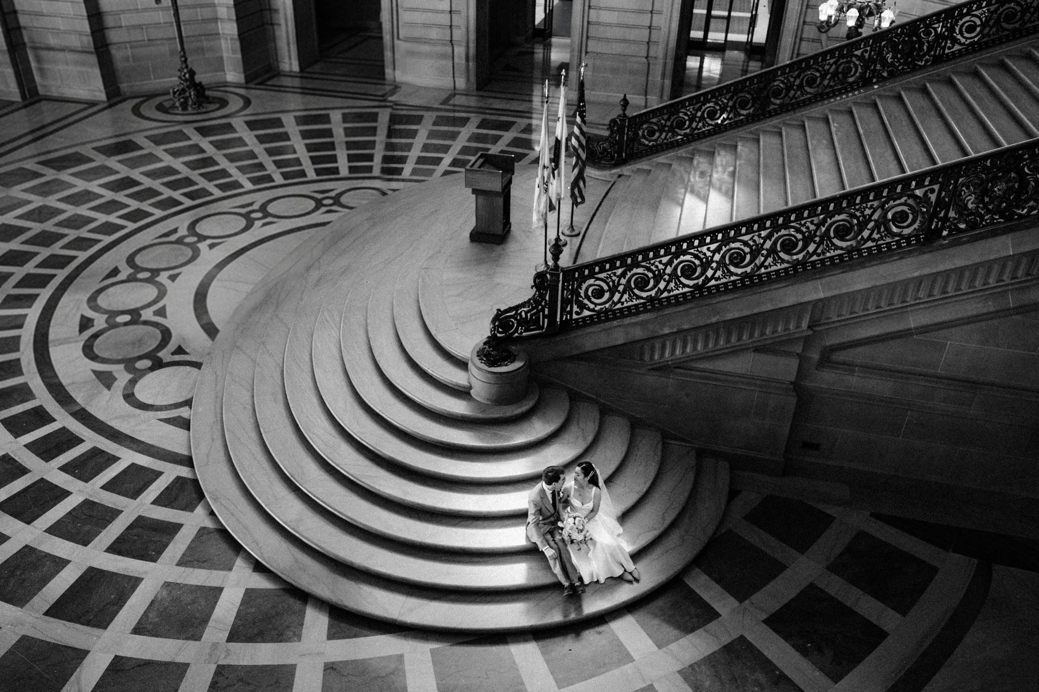 Bride and groom sitting at the bottom of staircase at San Francisco City Hall wedding