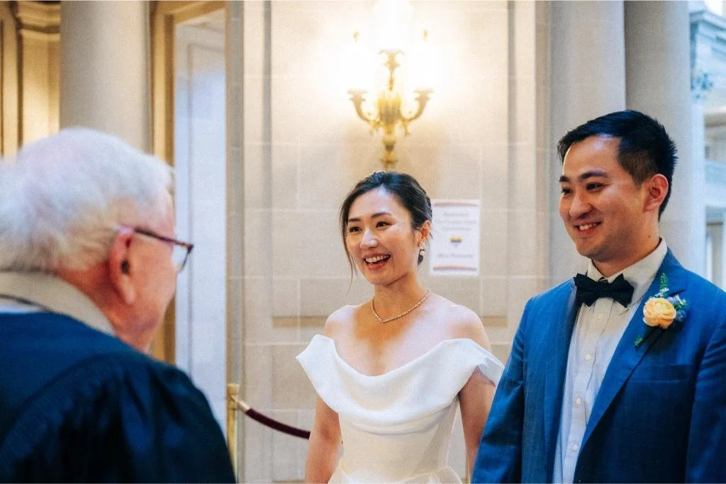 Bride and groom smiling beside each other during their civil wedding ceremony at San Francisco City Hall.