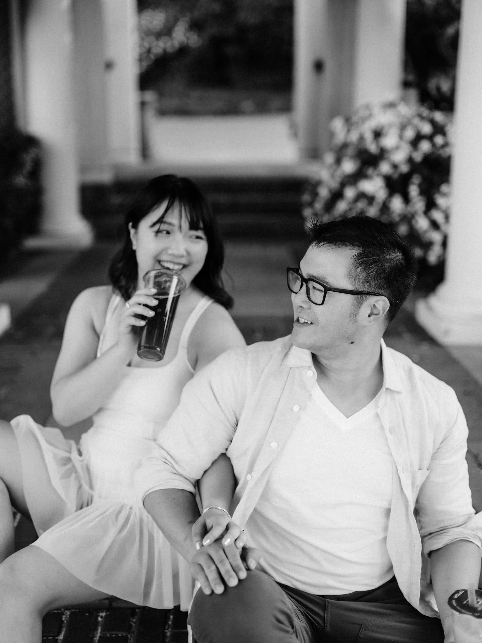 Couple sitting on the steps at Montalvo Arts Center in Saratoga holding hands while she drinks her tea.