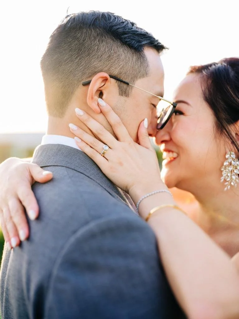 Bride and groom embracing with her wedding ring visible on his neck