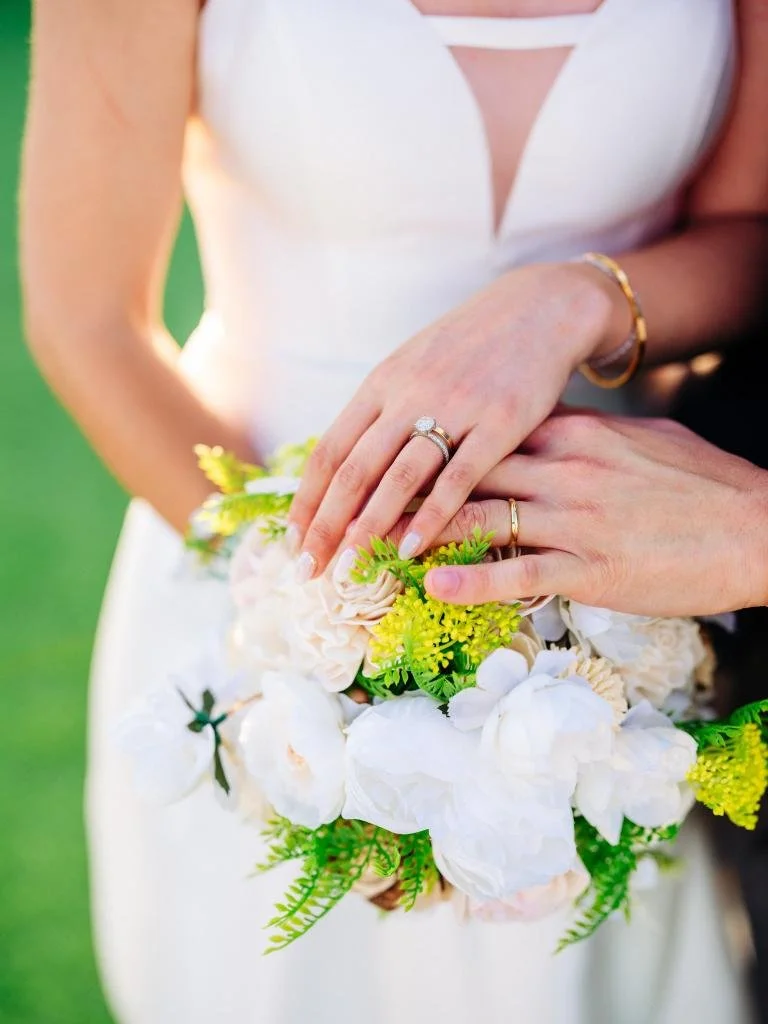 Close-up of the newlyweds holding hands with the bride's wedding ring visible