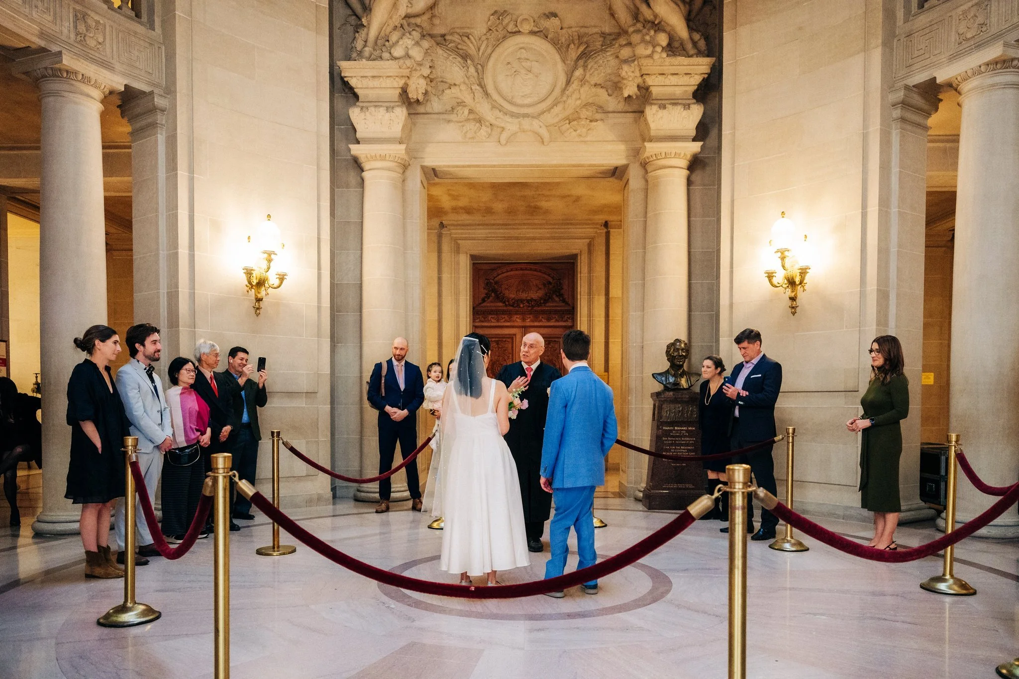 Back view of bride and groom listening to officiant during San Francisco City Hall wedding ceremony