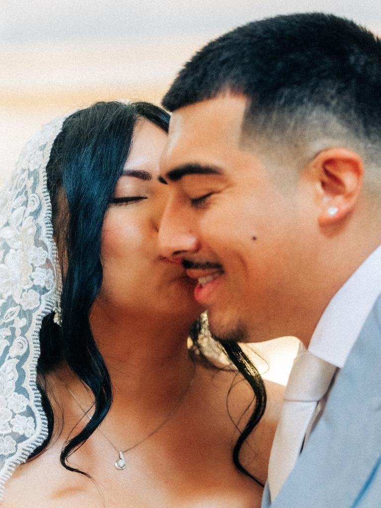 Close-up of bride kissing groom on the cheek during their San Francisco City Hall elopement