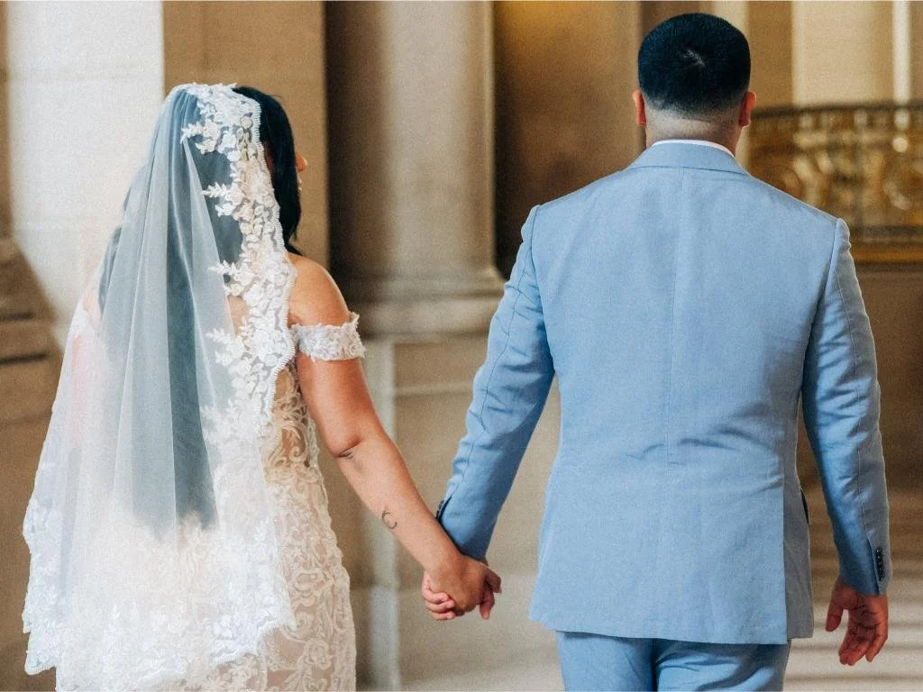 Bride and groom holding hands while walking through a hallway at San Francisco City Hall