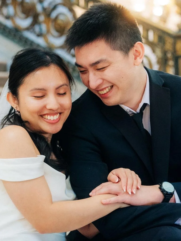 Alt: Bride and groom sitting on the stairs holding hands and smiling