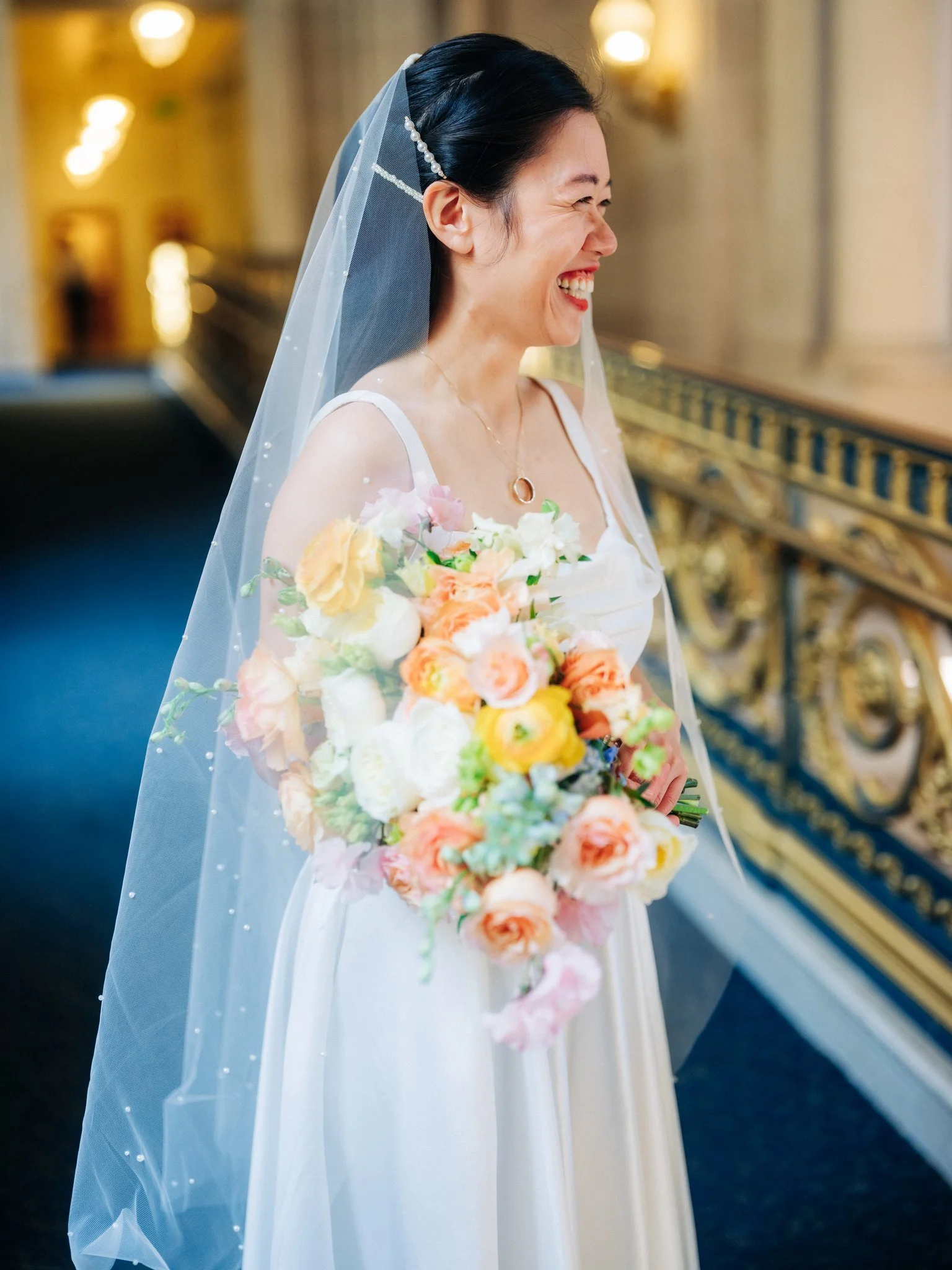 Bride smiling in profile holding flowers at San Francisco City Hall wedding