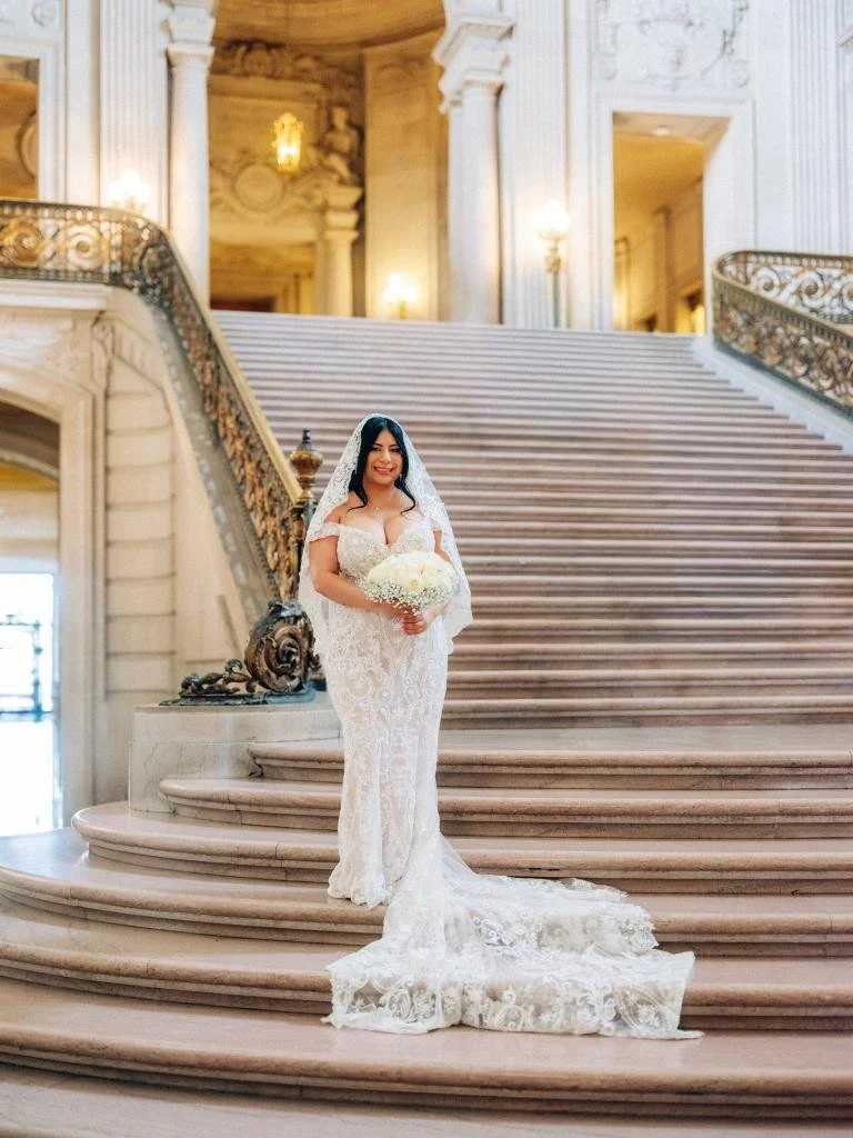 Bride standing alone at the bottom of the Grand Staircase at San Francisco City Hall