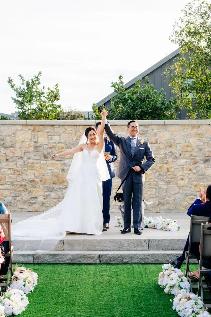 Newlyweds raising their joined hands after exchanging rings