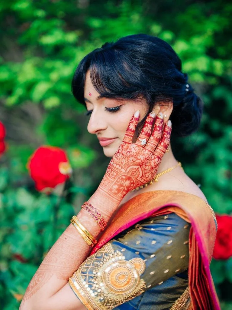 Bride posing with her hand near her face to show the detailed mehndi henna design