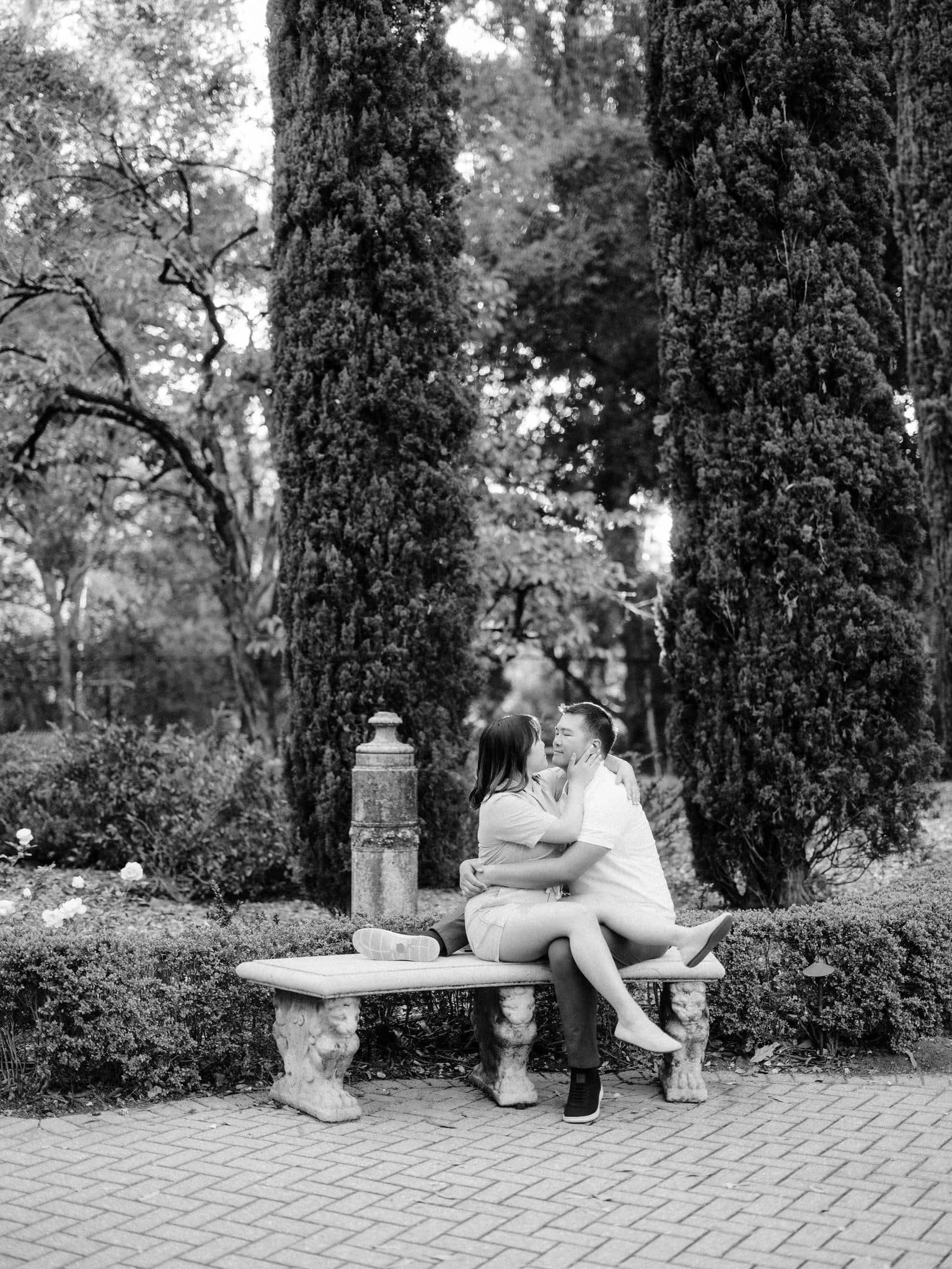 Couple sitting on a bench and embracing during their Montalvo Arts Center engagement photos in Saratoga.