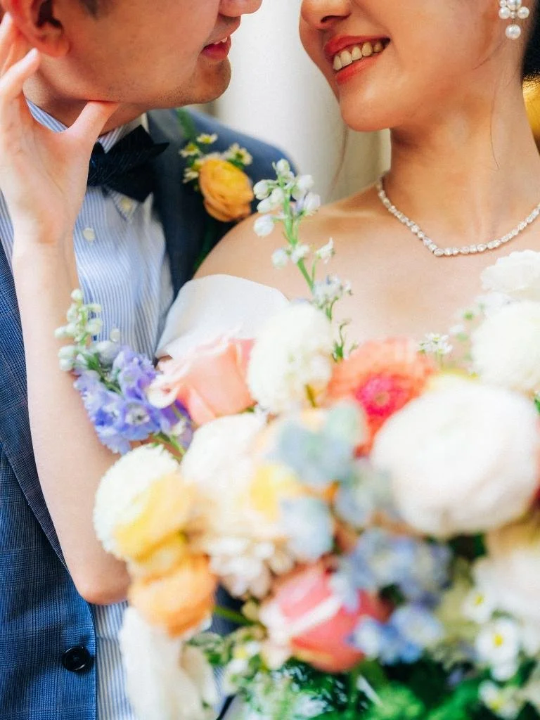 Close-up of the bride's bouquet as she touches the groom's face and they smile together.