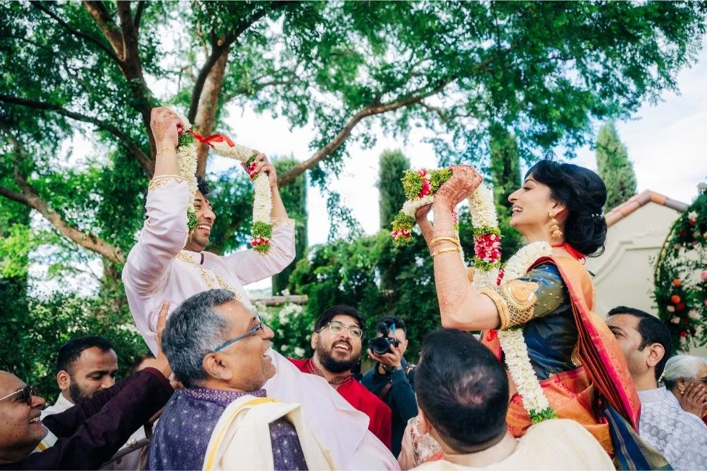 Bride and groom being lifted into the air by guests during the wedding celebration
