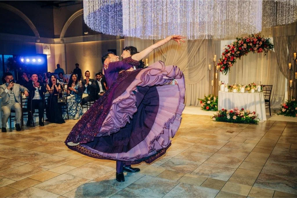 Bride and groom dancing together as her purple reception dress twirls