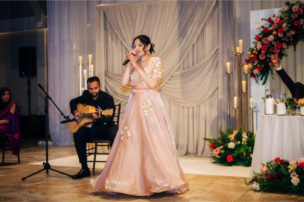 Wedding guest singing during a reception performance with a guitarist behind her