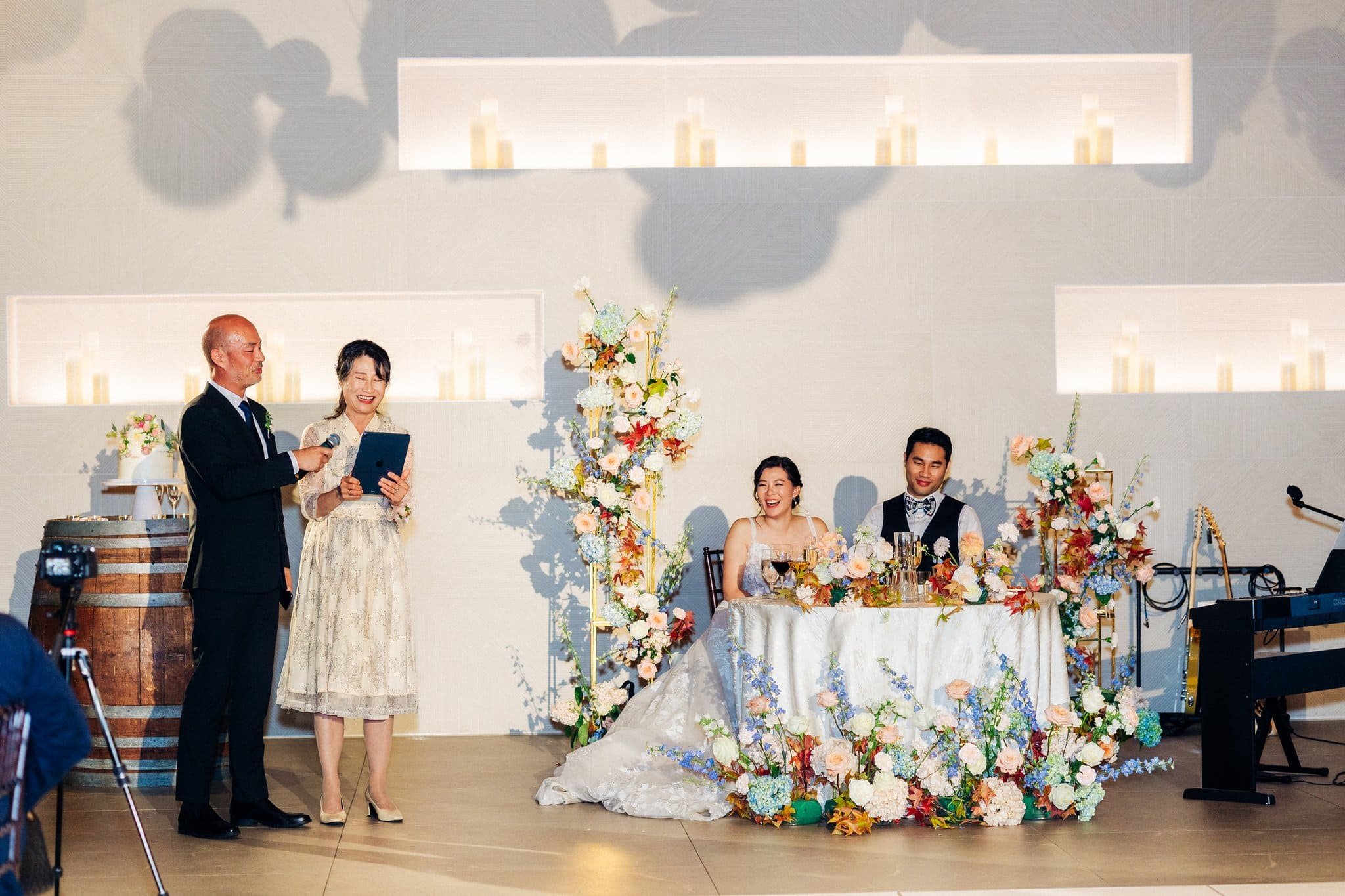 parents giving wedding speech with bride and groom laughing in background palm event center pleasanton reception