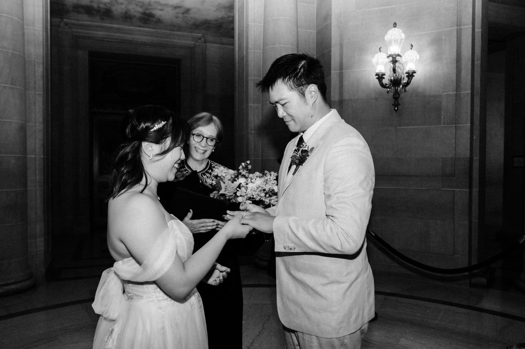 Bride placing a wedding ring on the groom during their San Francisco City Hall elopement ceremony.