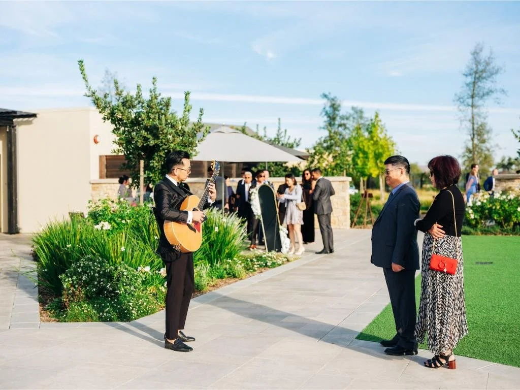 Guitarist playing live music as guests arrive for the wedding ceremony
