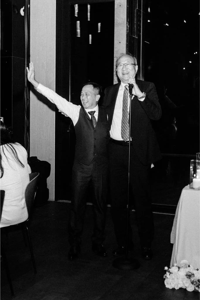 Two guests smiling while giving a speech during the wedding reception