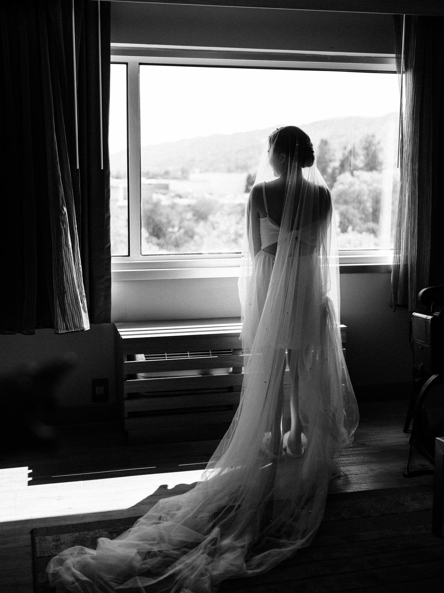 bride in wedding dress looking out window getting ready palm event center pleasanton ca