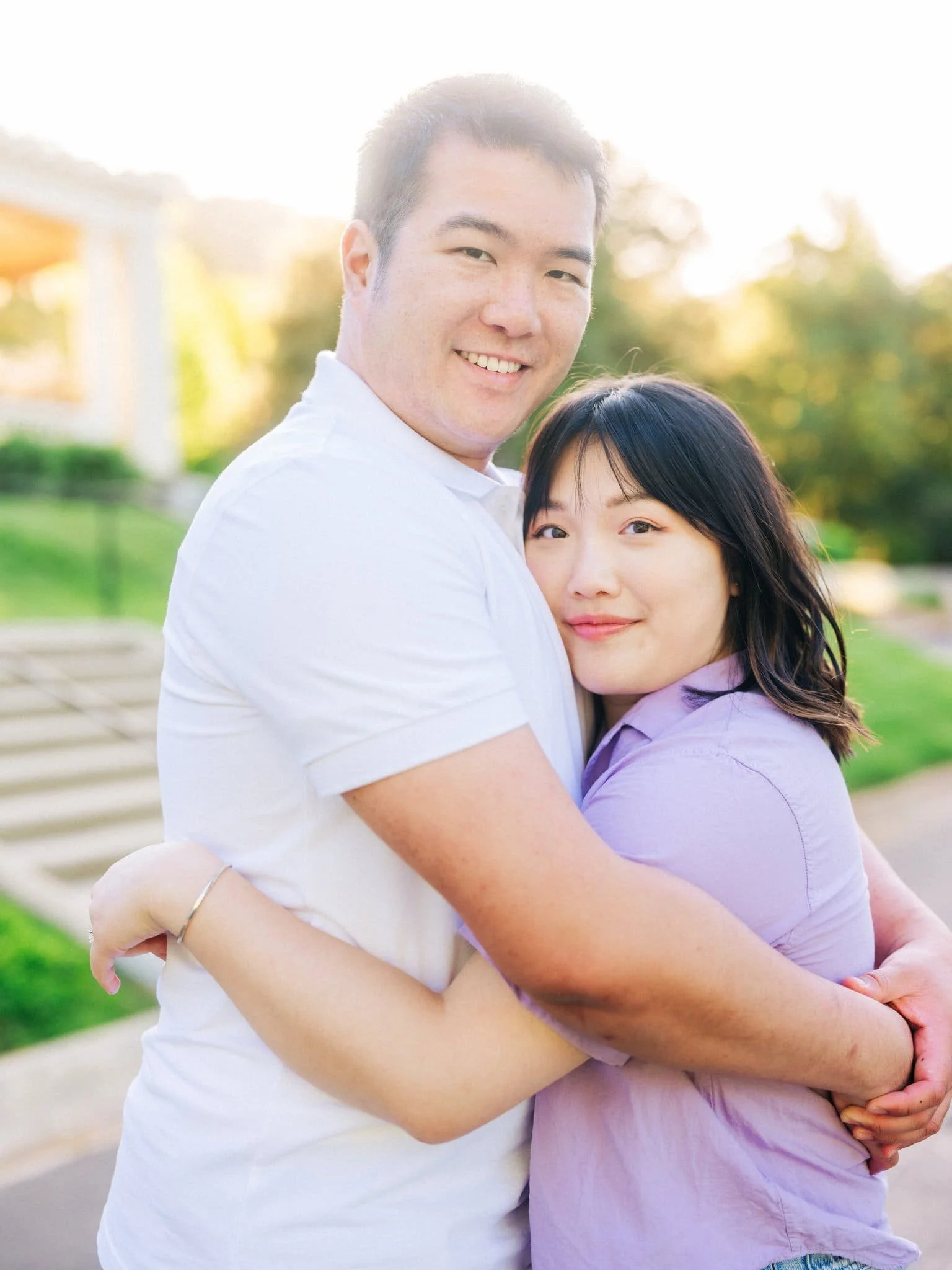 Couple hugging and smiling at the camera during their Montalvo Arts Center engagement photos in Saratoga.
