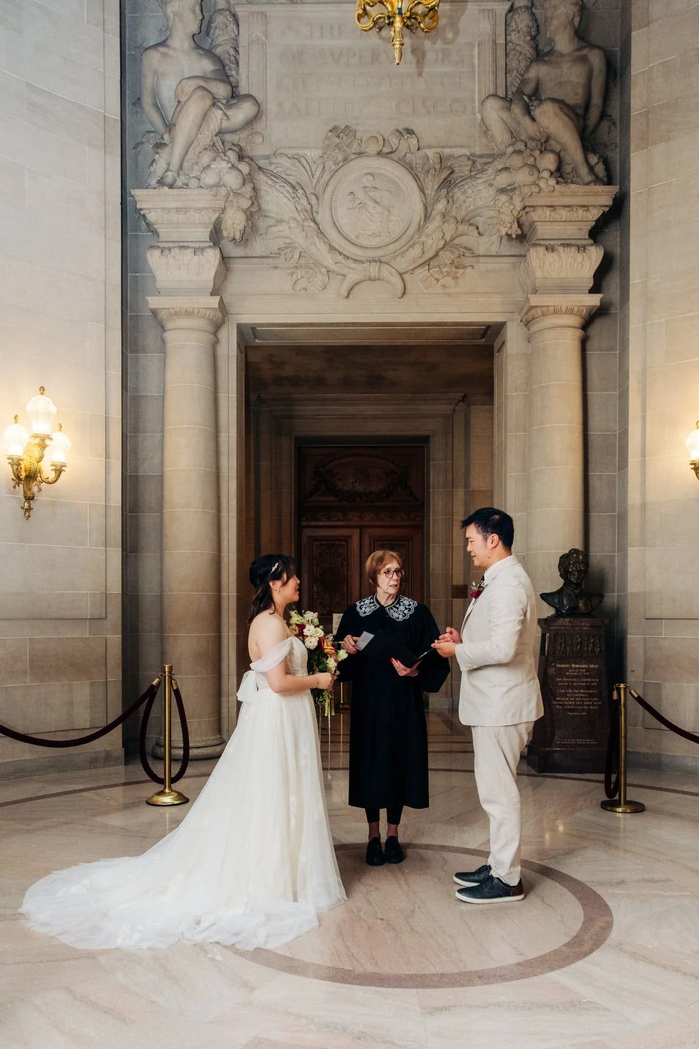 Bride and groom standing with their officiant during their San Francisco City Hall elopement ceremony.