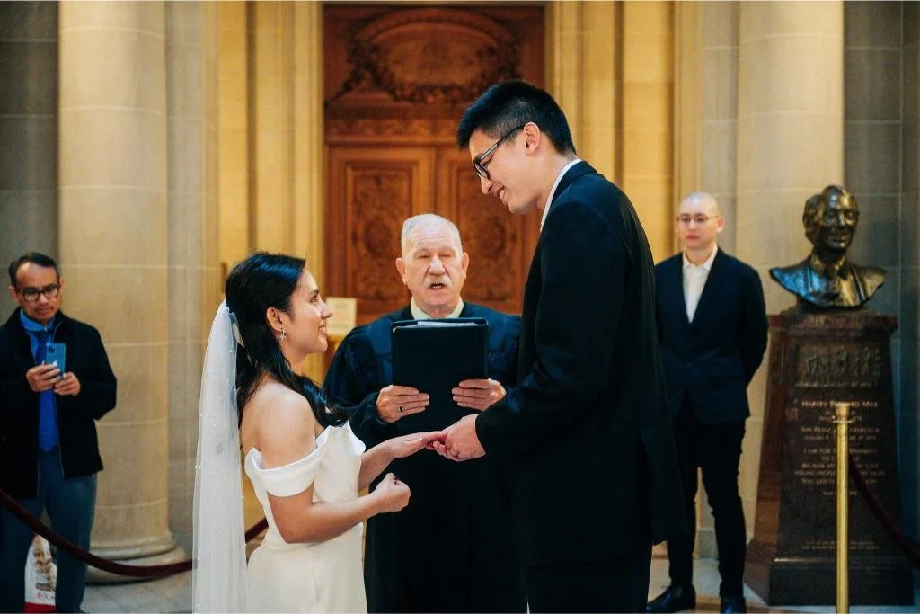 Groom placing a wedding ring on the bride's finger during their City Hall ceremony