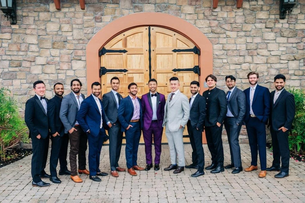 Groom and groomsmen posing together in suits during the wedding celebration