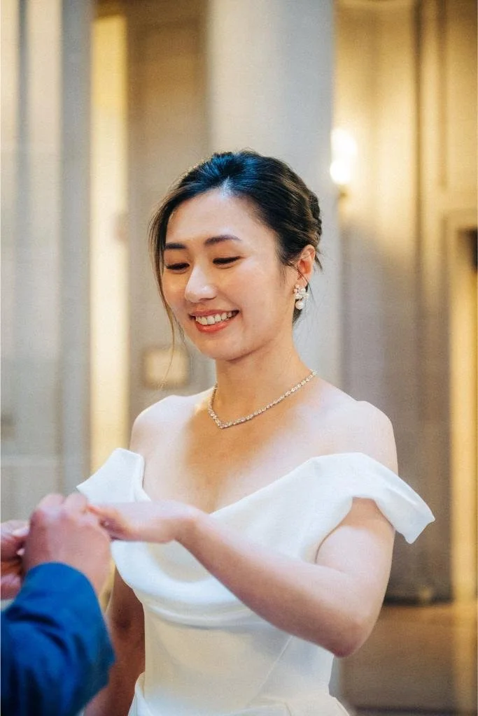 Groom placing a wedding ring on the bride's finger during their San Francisco City Hall ceremony.
