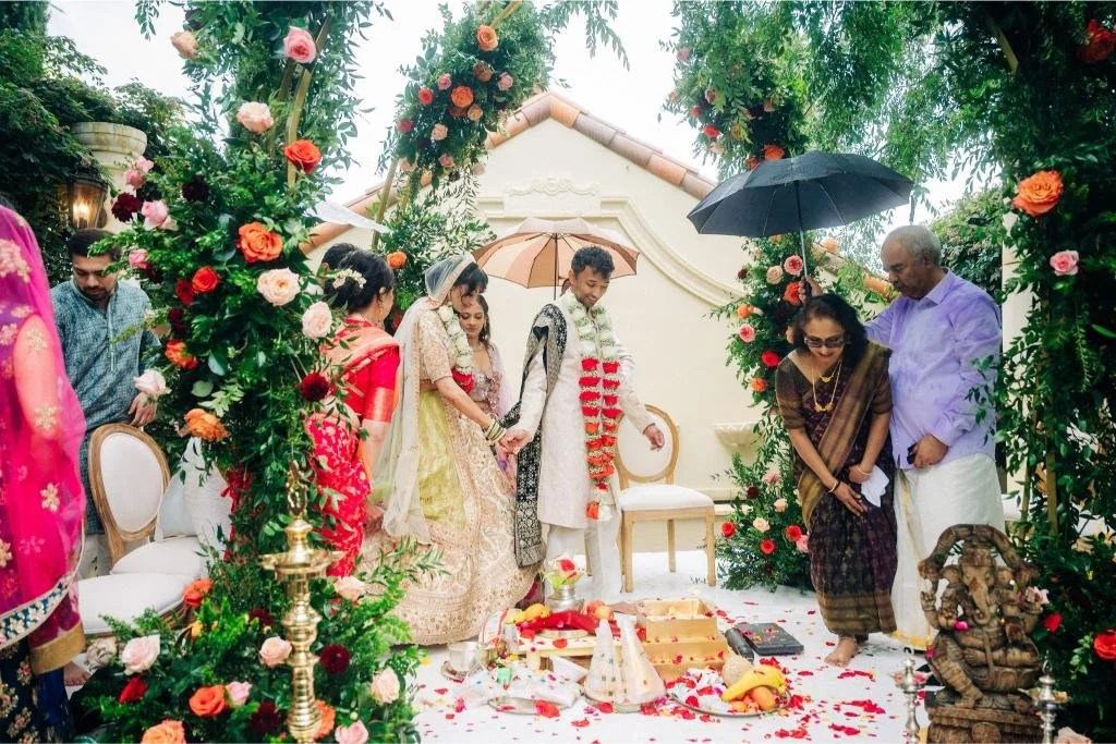 Bride and groom holding hands and looking down at flower petals during the ceremony