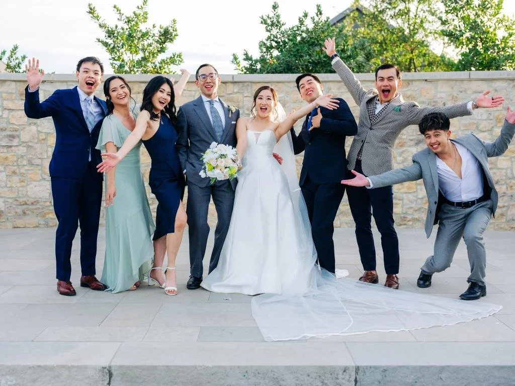 Bride and groom posing playfully for a group wedding photo