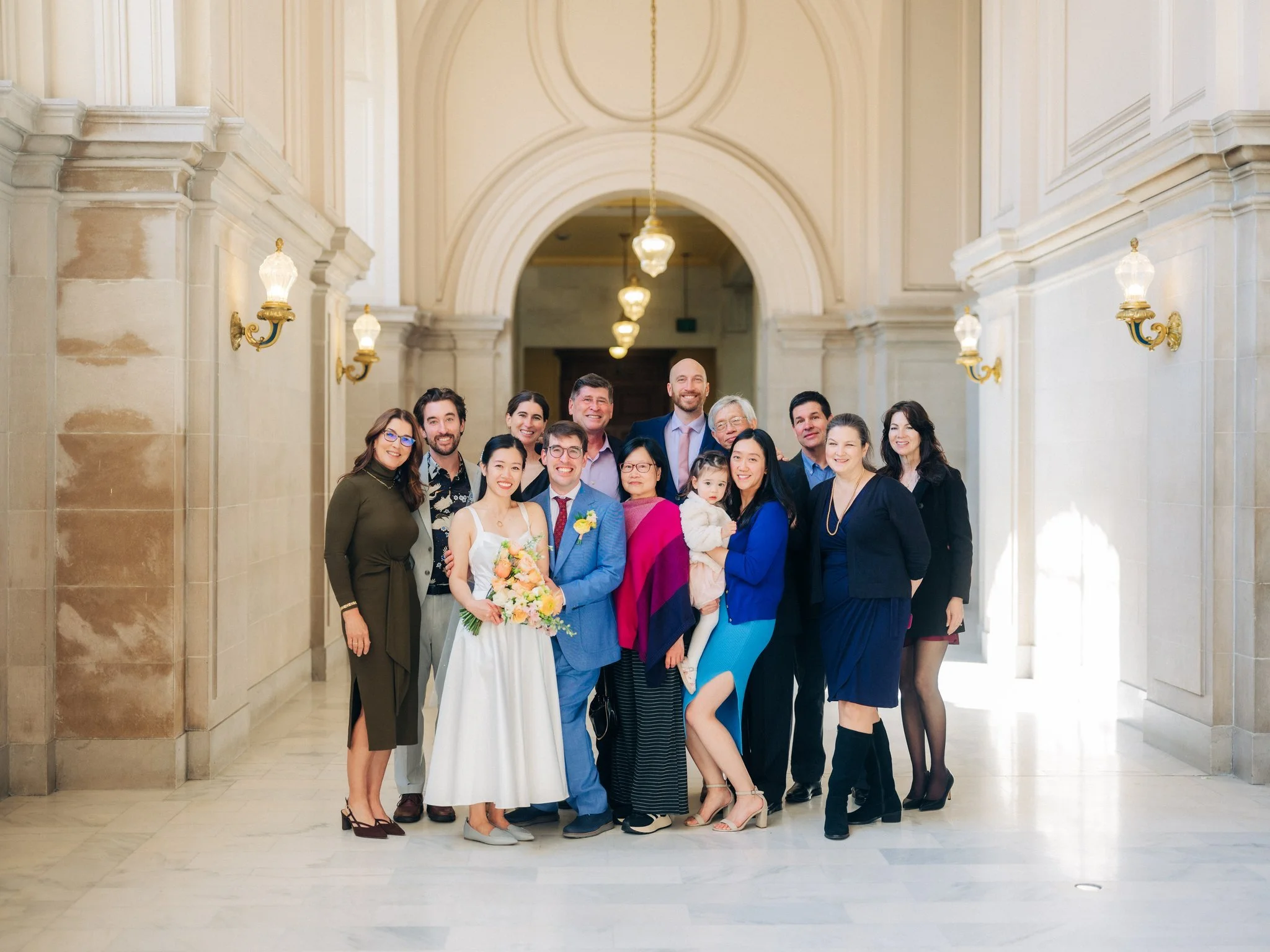 Bride and groom with guests in hallway at San Francisco City Hall wedding