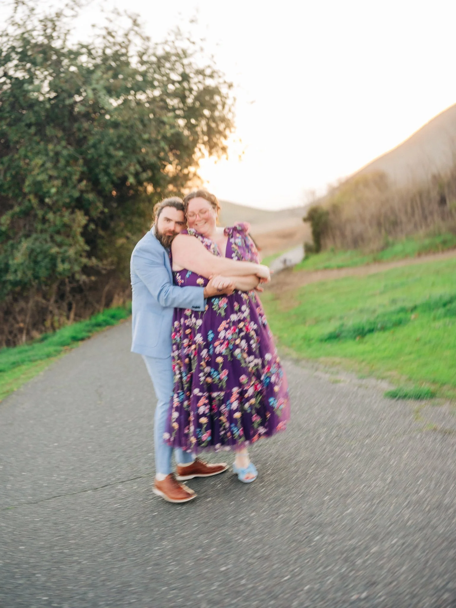 Man embracing his partner from behind with mountains in the background during a couples photo session at Coyote Hills Regional Park in Fremont CA