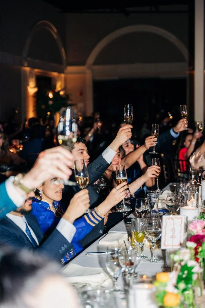Wedding guests raising champagne glasses together during the reception