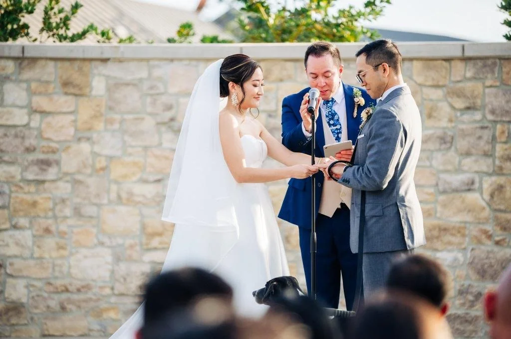Bride placing a wedding ring on the groom's finger during the ceremony
