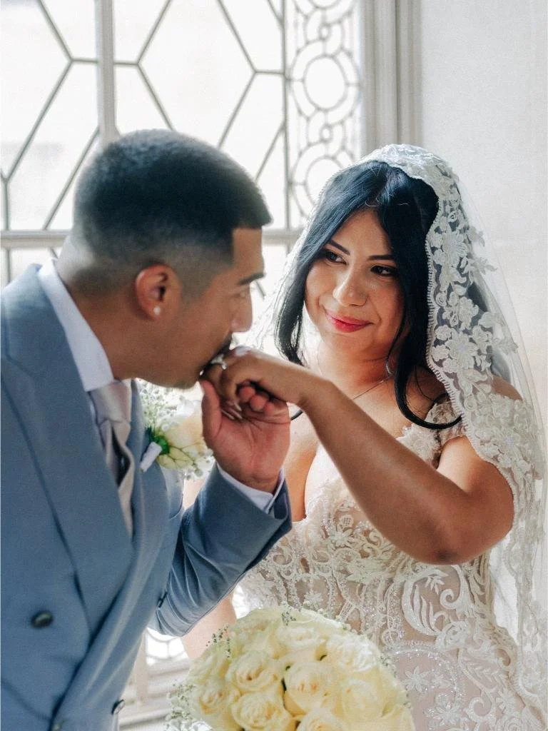 Groom taking the bride’s hand and kissing it.