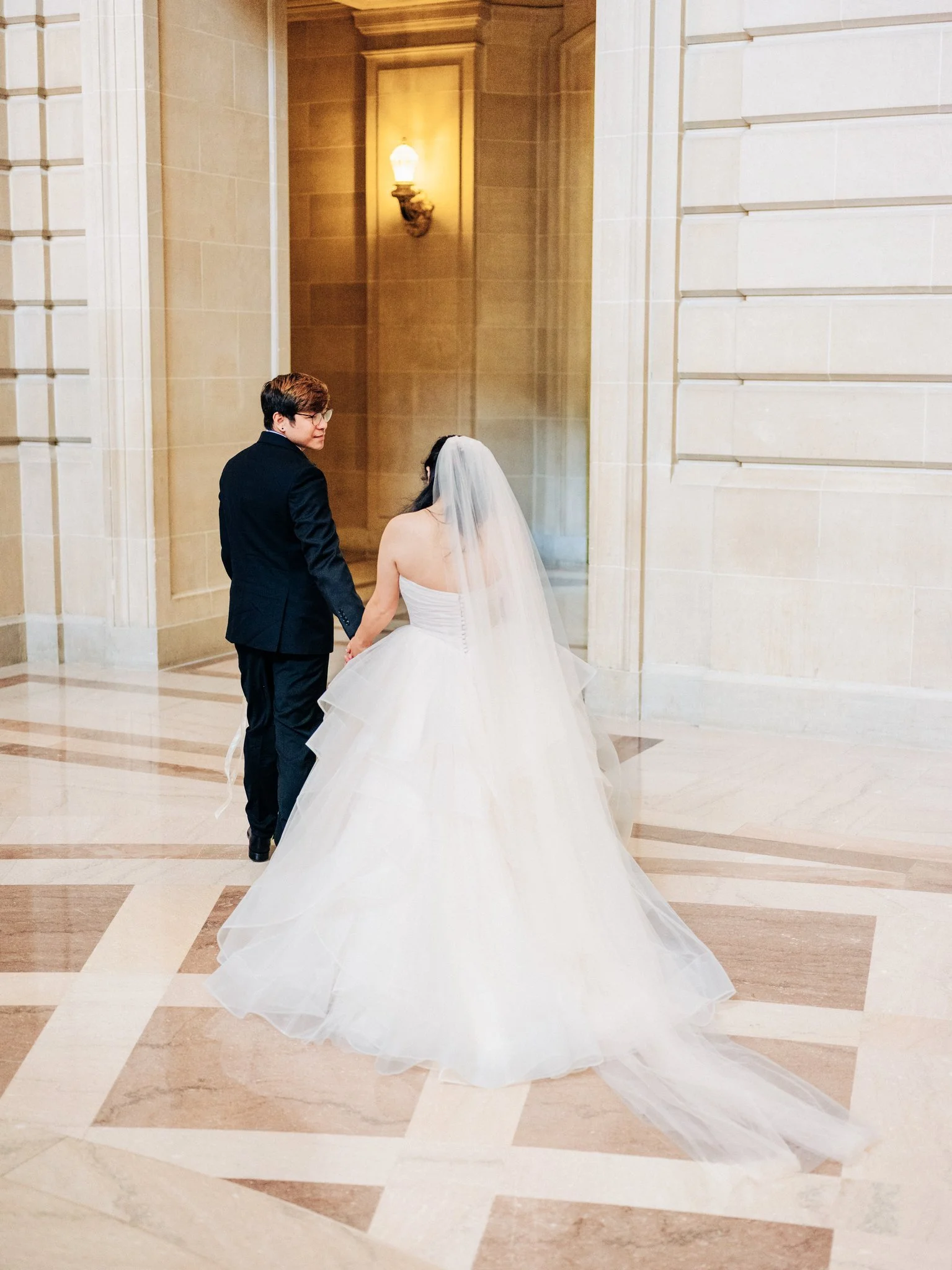 Bride and groom holding hands while walking through doorway at San Francisco City Hall wedding