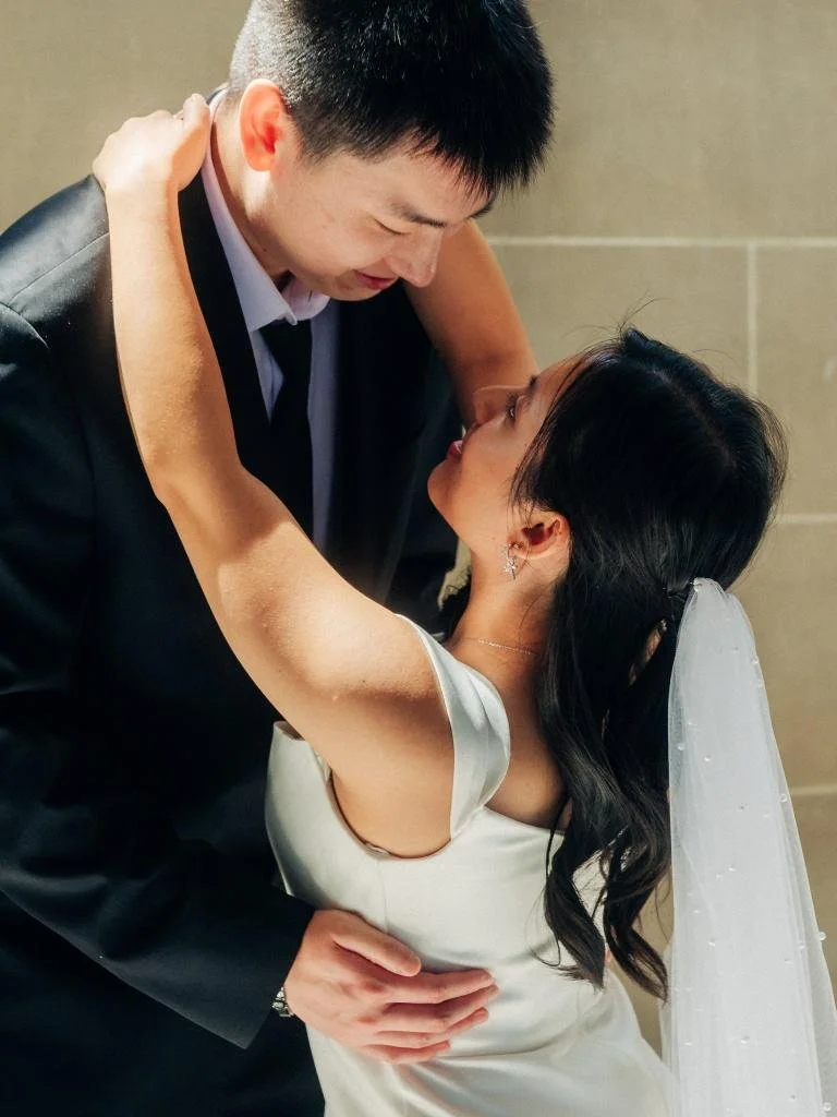 Bride reaching up to wrap her arms around the groom's neck inside San Francisco City Hall
