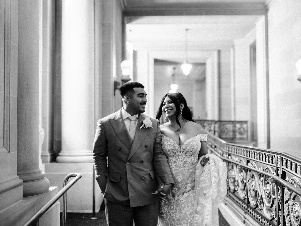 Bride and groom holding hands while walking together through San Francisco City Hall