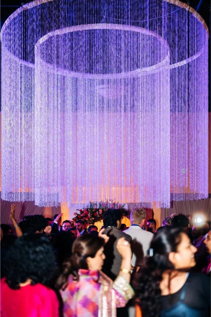Wedding guests dancing beneath a chandelier during the reception