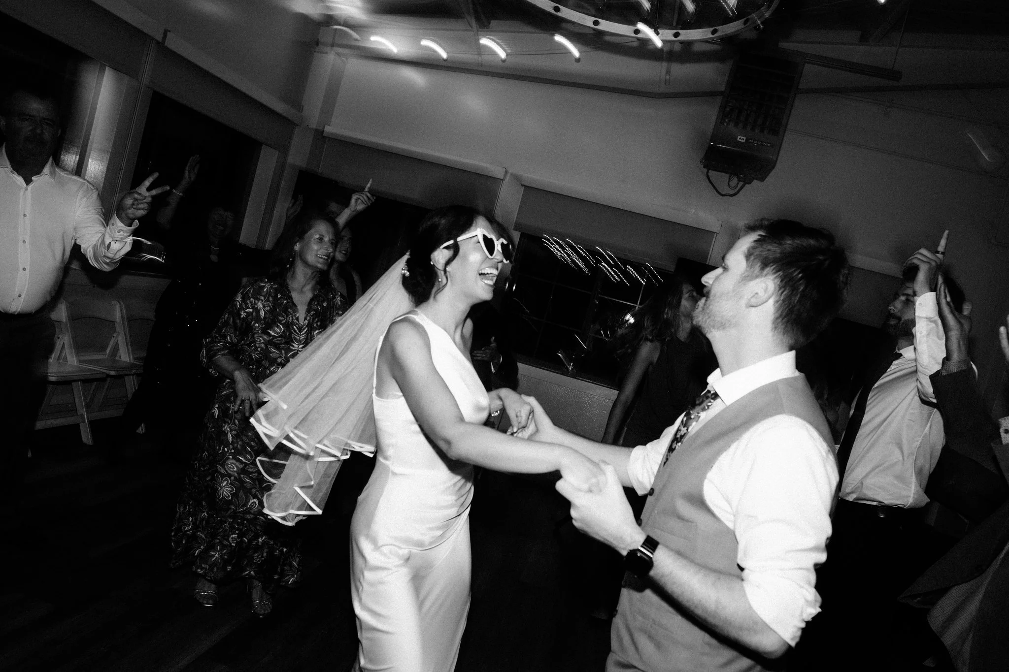 Bride and groom dancing with guests on the dance floor during their wedding reception at Maverick's Beach House in Half Moon Bay
