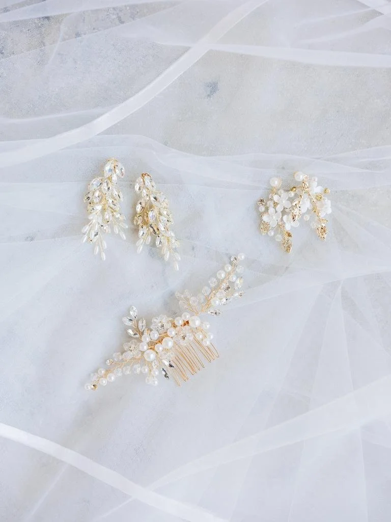 Earrings and pin photographed among the wedding details