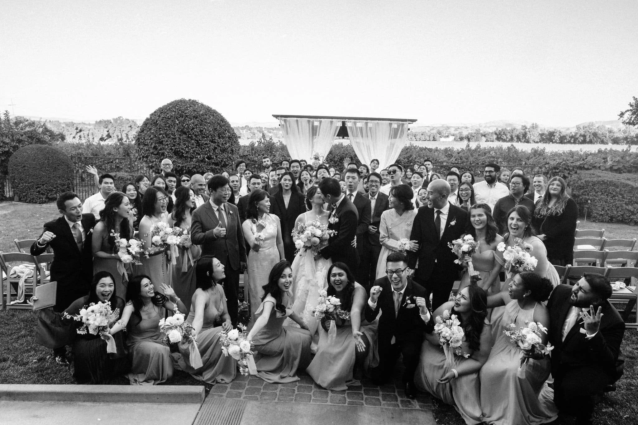 bride and groom kissing with all guests behind them group celebration palm event center pleasanton wedding